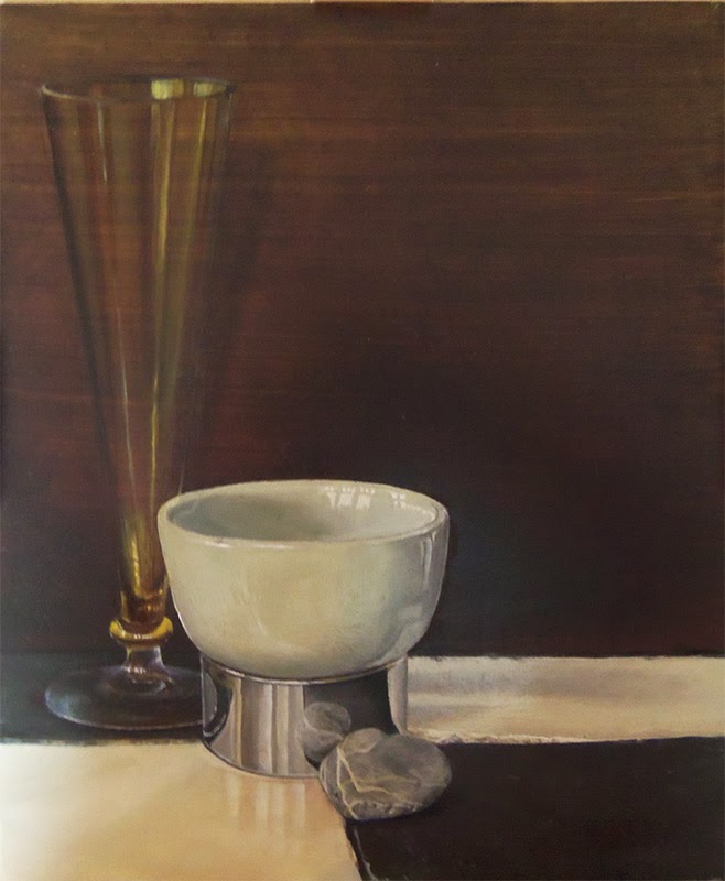 Une tasse blanche et un grand verre étroit, posés près d’une pierre sur une table.
